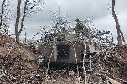 Imagen del 12 de abril de 2022 de un soldado ucraniano cubriendo un vehículo armado con ramas, en Donbass.