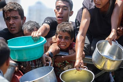 Imagen del 24 de agosto de 2025 de palestinos esperando para recibir alimentos gratuitos en un campo para personas desplazadas, en el suroeste de la Ciudad de Gaza. (Xinhua/Rizek Abdeljawad) (rtg) (ah) (ce)
