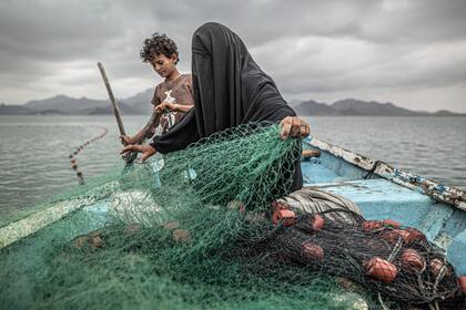 Imagen del argentino Pablo Tosco, titulada "Yemen: el hambre, otra herida de guerra", que ganó el primer premio en la categoría Temas Contemporáneos. Muestra a Fátima y su hijo preparando una red de pesca en un barco en la bahía de Khor Omeira, Yemen, el 12 de febrero de 2020