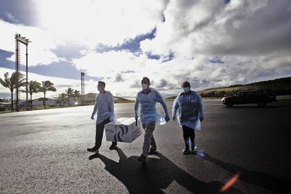 Imagen difundida por la Municipalidad de Rapa Nui que muestra a los trabajadores de la salud descargando una caja con casi 1200 dosis de la vacuna CoronaVac desarrollada por Sinovac, a su llegada al Aeropuerto Internacional de Isla de Pascua, en Rapa Nui, Chile, el 4 de febrero de 2021