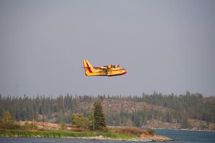 Un avión de extinción ayuda en la lucha contra los incendios forestales que asolan Yellowknife, Territorios del Noroeste, Canadá. Miles de personas a las que se les ordenó huir de los incendios forestales que avanzaban en una de las ciudades más grandes del extremo norte de Canadá