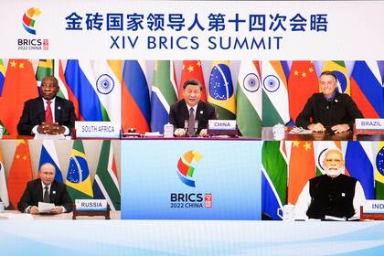 In this photo released by Xinhua News Agency, Chinese President Xi Jinping is seen on a screen with South African President Cyril Ramaphosa, Brazilian President Jair Bolsonaro, Russian President Vladimir Putin and Indian Prime Minister Narendra Modi as he hosts the 14th BRICS Summit via video link from Beijing, Thursday, June 23, 2022. Chinese President Xi Jinping opened a meeting of leaders of major developing countries on Thursday by saying the world should oppose unilateral sanctions and efforts by some countries to maintain their political and military power. (Li Tao/Xinhua via AP)