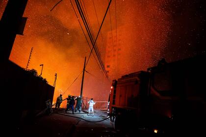 Los bomberos trabajan mientras un incendio forestal afecta los cerros de Viña del Mar, donde se ubican cientos de casas, en la Región de Valparaíso
