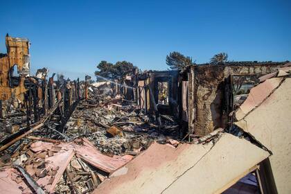 Un bombero limpia con una manguera en una de las más de 30 casas destruidas por el Incendio Costero en Laguna Niguel, California