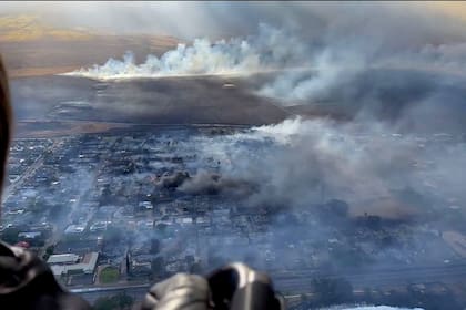 El humo sale de los edificios destruidos mientras los incendios forestales arden en Maui