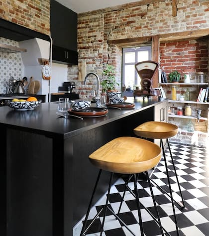 Incorporaron muebles pintados de negro en la cocina para contrastar con las claras paredes de ladrillo viejo
