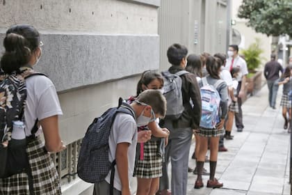 Los alumnos hacen cola respetando la distancia social para ingresar a la escuela