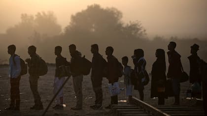 Inmigrantes y refugiados hacen cola para cruzar de Grecia a Macedonia, cerca de Gevgelija