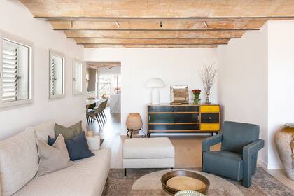 Insertado en las vigas, un riel con luces orientables 'Track' (Flos), sillón 'Utrecht' (Cassina) y lámpara 'Atollo' (Oluce). El vano deja ver el comedor, la cocina y la terraza posterior.