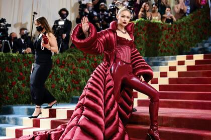 Inspirada en el glamour de la Edad Dorada de Estados Unidos, específicamente de la ciudad de Nueva York, Gigi Hadid llegó a la Met Gala 2022 con unos leggins de vinilo, un corset, unas botas altas de taco fino y un increíble tapado acolchado y satinado. Todo en un llamativo color burdeos
