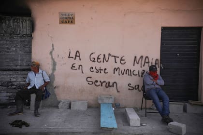 Integrantes del grupo de autodefensas conocido como "El Machete" se sientan junto a un grafiti
