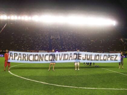 Integrantes del organismo de DDHH del club posando con la bandera en la previa de un partido