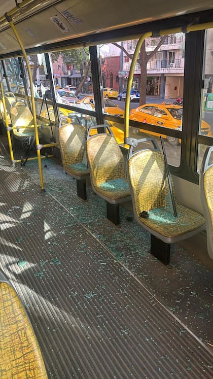 Interior del colectivo con asientos cubiertos de vidrios rotos