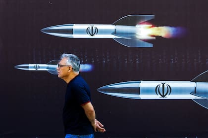 Un hombre pasa junto a una pancarta que representa misiles a lo largo de una calle de Teherán el 19 de abril de 2024
