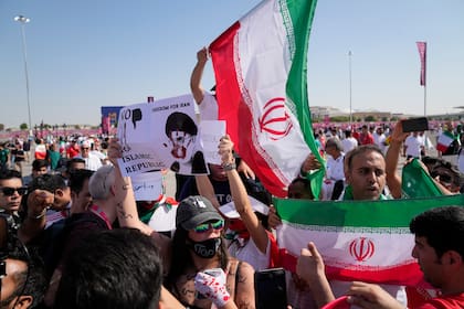 Seguidores ondean banderas iraníes y una mujer sostiene un cartel en el que se lee "Libertad para Irán, no a la República Islámica", antes del partido de fútbol del grupo B del Mundial entre Gales e Irán, en el estadio Ahmad Bin Ali de Al Rayyan, Qatar, viernes 25 de noviembre de 2022.
