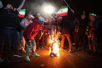Iraníes queman banderas de Estados Unidos e Israel mientras reaccionan tras el anuncio del alto el fuego en la plaza Enqelab, en Teherán, el 8 de abril de 2026
