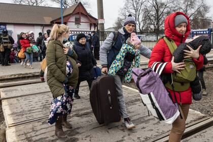 Mientras los hombres se quedan atrás para luchar, las mujeres y los niños que huyeron de los combates en Bucha e Irpin se apresuran a abordar un tren de evacuación. Los intensos combates durante la noche obligaron a muchos a abandonar sus hogares en Irpin, Ucrania