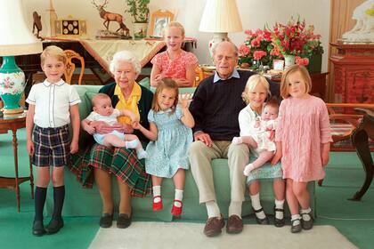 Isabel y Felipe en 2021, en uno de los roles que los hacían felices: el de bisabuelos. La Reina tuvo doce bisnietos, de los cuales siete están en la foto. De izquierda a derecha: el príncipe George, el príncipe Louis en brazos de Su Majestad, Savannah Phillips (de pie, detrás del sillón), la princesa Charlotte, Isla Phillips con Lena Tindall y Mia Tindall. 