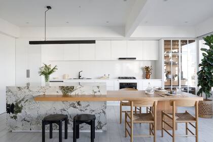 Isla con paneles exteriores de cuarcita ‘Alpinus’ (Canteras del Mundo ejecutado por Marmolería Altamar) con mesa enchapada en roble con terminación de laca poliuretánica (Octava Arquitectura). Bancos ‘Orno’ (Ries) y sillas de roble americano (Broca).