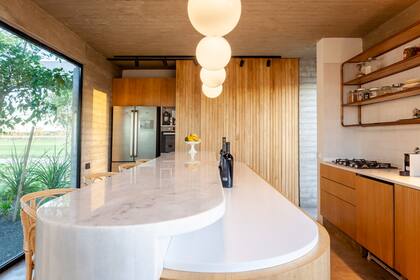 Isla de kiri con mesada a 1,10 m. de altura con tapa de mármol ‘Blanco Turco’; la más baja, de Corian, al igual que la mesada principal con mueble de kiri (Leone Loray)