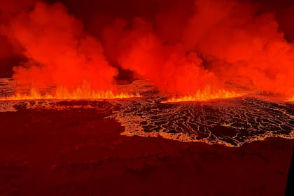 Humo y lava que fluye, tornando el cielo de color naranja durante una erupción volcánica en la península de Reykjanes, a 3 km al norte de Grindavik, al oeste de Islandia, el 18 de diciembre de 2023.