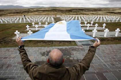 El veterano de guerra Marcelo Marani hace ondear una bandera argentina durante su visita al cementerio de Darwin