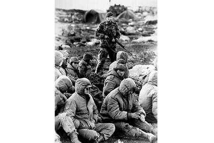 Soldados argentinos capturados custodiados por un Royal Marine británico, el 2 de junio de 1982