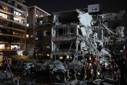 Tropas israelíes y personal de emergencia se reúnen frente a un edificio alcanzado por un misil lanzado desde Irán, en Tel Aviv, el 13 de junio de 2025