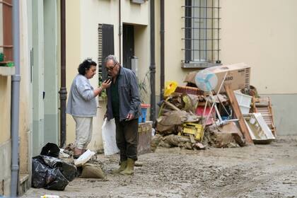 La gente se encuentra en un camino cubierto de lodo en Faenza, Italia, el jueves 18 de mayo de 2023