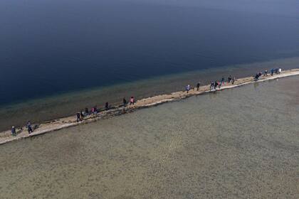 Una foto aérea muestra a personas caminando hacia la pequeña isla de San Biagio, frente a Manerba del Garda.
