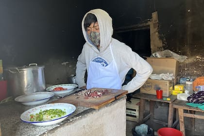 Iván prepara un guiso de papa verde, una comida ancestral, mientras Carmen Chañi, la coordinadora pedagógica, lo filma con su teléfono