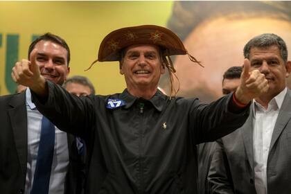 Jair Bolsonaro (centro), antes de ser presidente de Brasil, junto a su hijo, el senador Flavio Bolsonario (izquierda) ) y el presidente del Partido Social Liberal Gustavo Bebianno