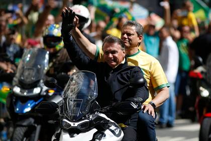 Jair Bolsonaro conduce una moto durante un acto de campaña en Campinas, en Sao Paulo; detrás, cientos de seguidores con la camiseta verde-amarilla