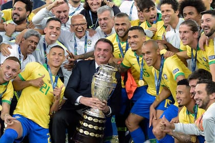 Jair Bolsonaro, presidente de Brasil, festeja con la selección la obtención del trofeo en la Copa América de 2019; dos años después, el certamen volverá a jugarse en territorio brasileño