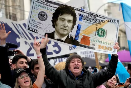 Javier Milei muestra un billete de cien dólares con su rostro durante una caravana libertaria por La Plata