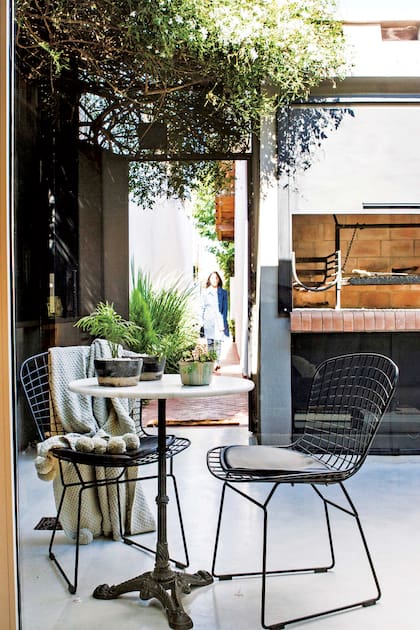 Escondida detrás de un pequeño muro, al lado de la puerta se ubicó una parrilla y también un box cerrado que aloja el lavarropas, el termotanque y la pileta de lavar.