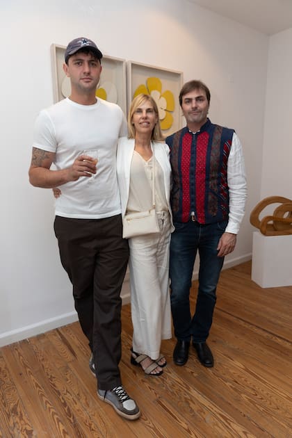 Jerónimo Pando con Alejandra Hoeffner y Eduardo Blaquier, primos de su mamá, Ginette Reynal. Detrás de ellos, tres obras de Alejandra: las flores y una escultura de madera