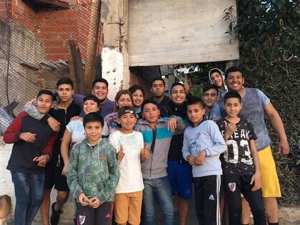 Jesica Medina (tapada por el chico de gorrita para atrás) en la puerta de su casa y del club, con parte del equipo y otros voluntarios