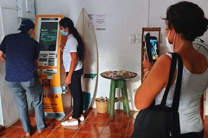 Jessica Velis enseña cómo usar uno de los dos únicos cajeros de bitcoin que existen en El Salvador a todos los interesados, que graban emocionados la experiencia