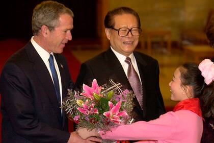 George W. Bush recibe flores mientras Jiang Zemin lo saluda a su llegada a Pekín, el 21 de febrero de 2002