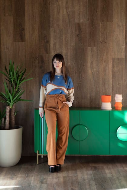 Jimena Frontera, creadora de @jimefrontera, la cuenta desde donde habla de temas relacionados con el amor propio y la maternidad. Sobre el mueble verde (Laly Lezcano), objetos decorativos (Familia:DDD).