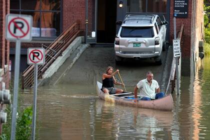 Jodi Kelly y su esposo Dan Kelly usan una canoa para navegar por las calles inundadas de Montpelier, Vermont, el 11 de julio de 2023.