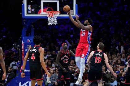 Joel Embiid, de los 76ers de Filadelfia, salta para encestar ante Scottie Barnes, Pascal Siakam (43) y Jakob Poeltl, de los Raptors de Toronto, en el encuentro del viernes 31 de marzo de 2023 (AP Foto/Matt Rourke)