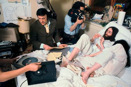 John Lennon y Yoko Ono en 1969 en la cama del Hotel Queen Elizabeth, en Montreal, mientras el legendario DJ de Nueva York Murray the K transmite en vivo y un camarógrafo los filma