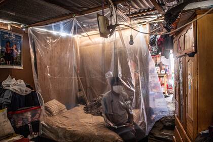 Jonathan, de 30 años, se sienta en su cama detrás de una protección plástica mientras los médicos realizan una ronda de visitas en Ate, en las afueras del este de Lima, el 10 de septiembre de 2020, en medio de la pandemia del nuevo coronavirus