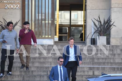 Jonathan Kovalivker, en el centro, de saco y sin corbata, saliendo ayer de Comodoro Py, donde entregó su teléfono celular