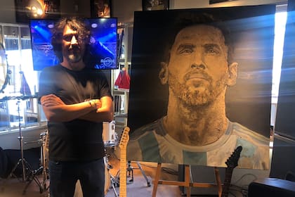 Jorge Coqui López pusa junto al retrato que hizo de Messi, con tierra de su casa natal