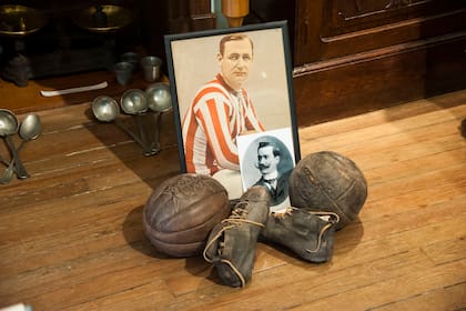 Jorge Gibson Brown, el de la foto a color, fue el Messi de la época,.tanto para Alumni como para los primeros seleccionados argentinos, de los que fue capitán. En la foto blanco y negro William Allerton Jordan. Las pelotas y los botines eran importados de Gran Bretaña. Los objetos pertenecen al coleccionista Martín de Vita.