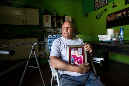 Jorge Rego, en su casa, con la foto de su hijo, Cristopher, y las paredes y los estantes que muestran la pasión de ambos por Huracán