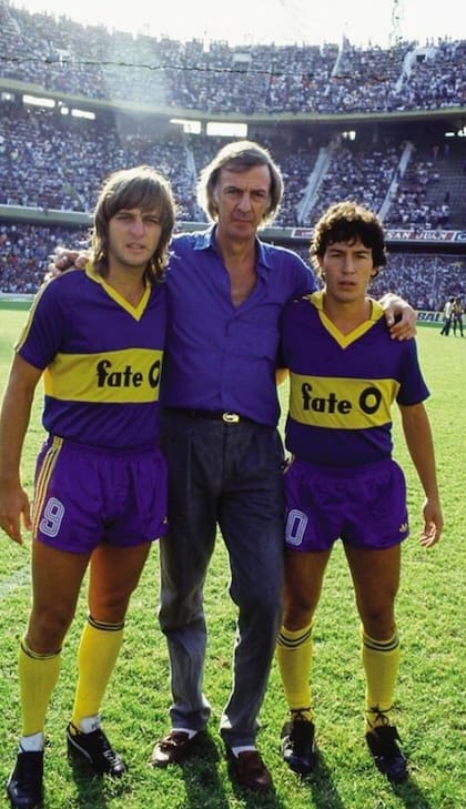 Jorge Rinaldi y Carlos Daniel Tapia, junto al DT César Luis Menotti, con la camiseta de Boca Juniors y el logo de FATE